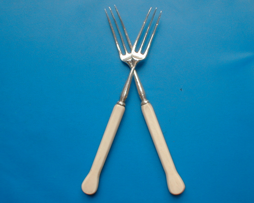 A pair of silver and ivory forks.
